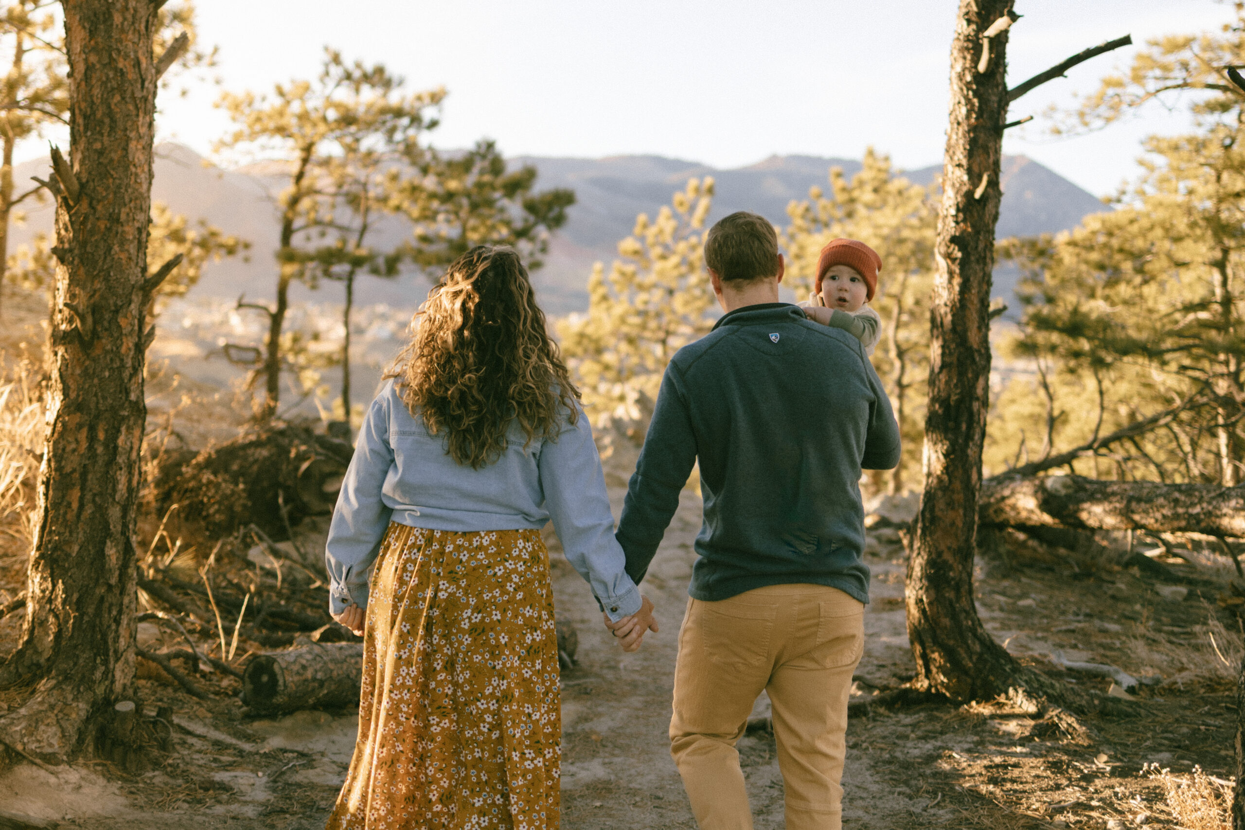 Couple holding hands walking away on a scenic overlook trail at sunset